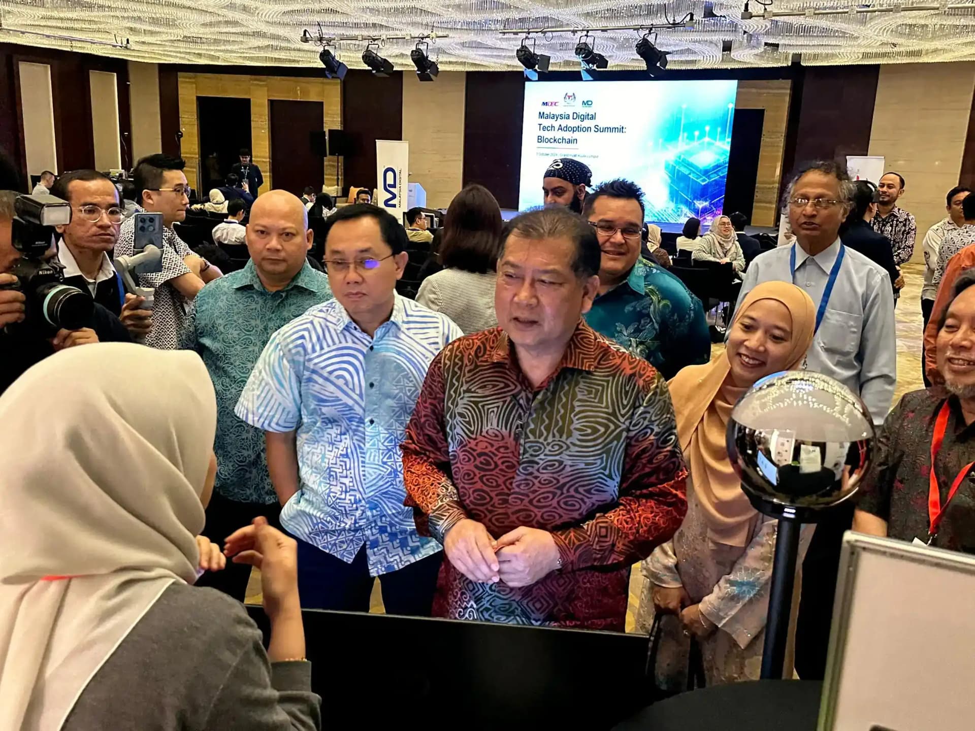 KUALA LUMPUR, 3 OKTOBER 2024 – Timbalan Menteri Kementerian Digital, YB Datuk Wilson Ugak Anak Kumbong telah merasmikan The Malaysia Digital Tech Adoption Summit: Blockchain. Sidang kemuncak tersebut merupakan anjuran Malaysia Digital Economy Corporation (MDEC), iaitu agensi utama ekonomi digital di bawah Kementerian Digital. Perasmian tersebut telah dilakukan di Grand Saloon, Level 1, Grand Hyatt Kuala Lumpur.  Program ini bertujuan untuk menggalakkan kerjasama antara pemain industri serta mempromosikan integrasi teknologi Blockchain merentasi pelbagai sektor di Malaysia. Acara ini akan menampilkan kemajuan terkini, menyerlahkan potensi transformasi dan membuka jalan ke arah ekonomi digital yang lebih berdaya tahan serta saling berkaitan.